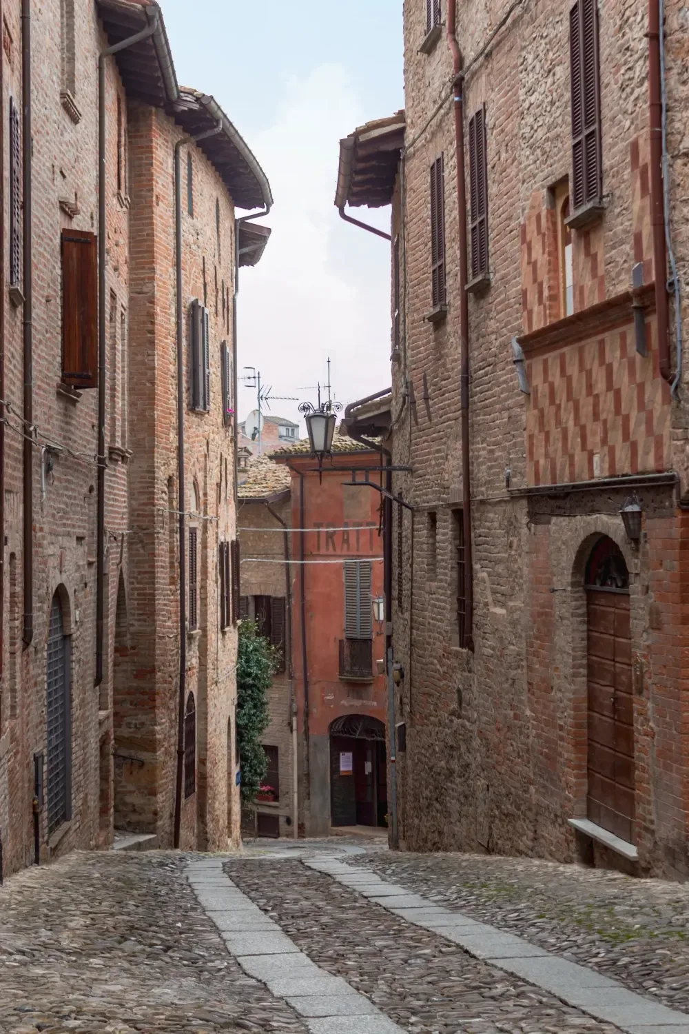 Un vicolo acciottolato in salita di Castell’Arquato, fra le case in pietra e laterizio del centro storico